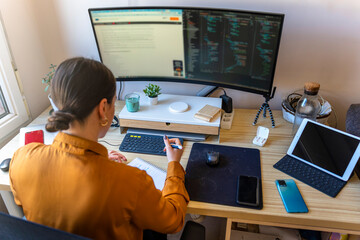 Computer programmer working from home. Teleworking concept. Business woman taking notes.