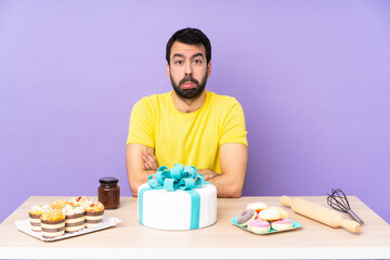 Man in a table with a big cake with sad and depressed expression