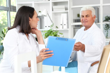 Poster - Doctors discussing something at their workplaces in medical office