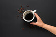 © Pixel-Shot - Woman holding cup of hot coffee and beans on black background