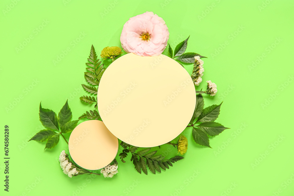 Composition with blank paper sheets and beautiful flowers on green background