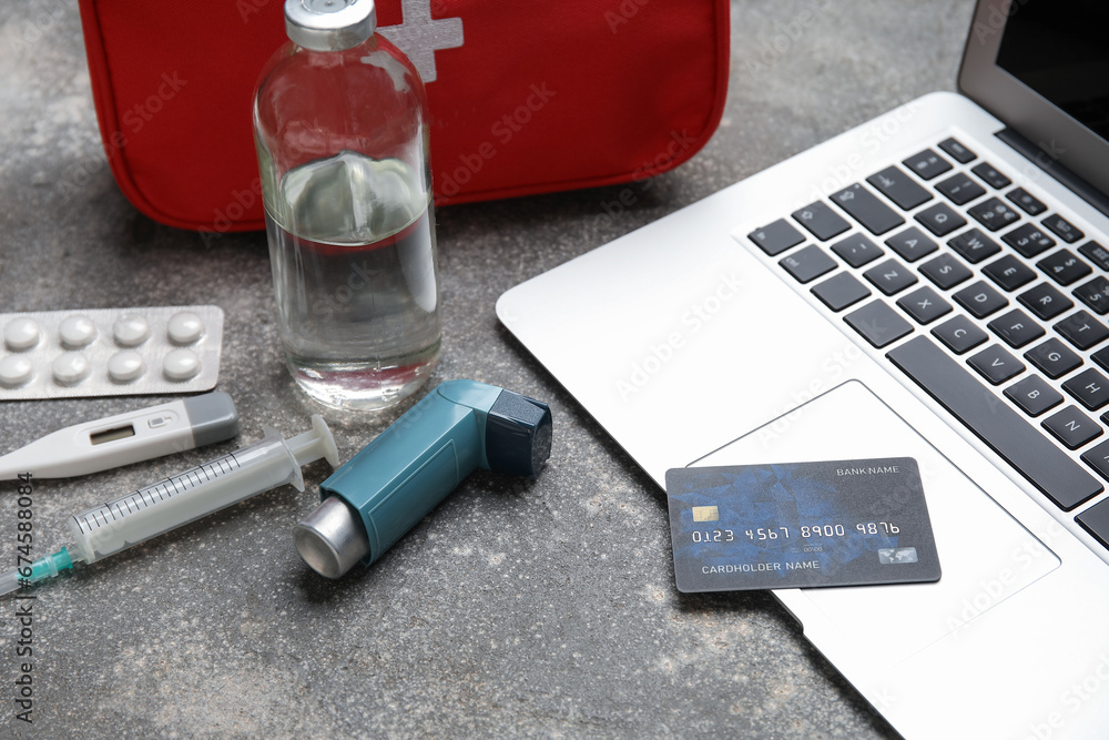 Laptop, credit card and first aid kit on grunge grey background