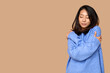 © Pixel-Shot - Young Asian woman hugging herself on brown background
