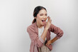 © Reezky - A young beautiful Asian woman employee wearing cardigan is shouting and screaming loud with a hand on her mouth, isolated by white background.