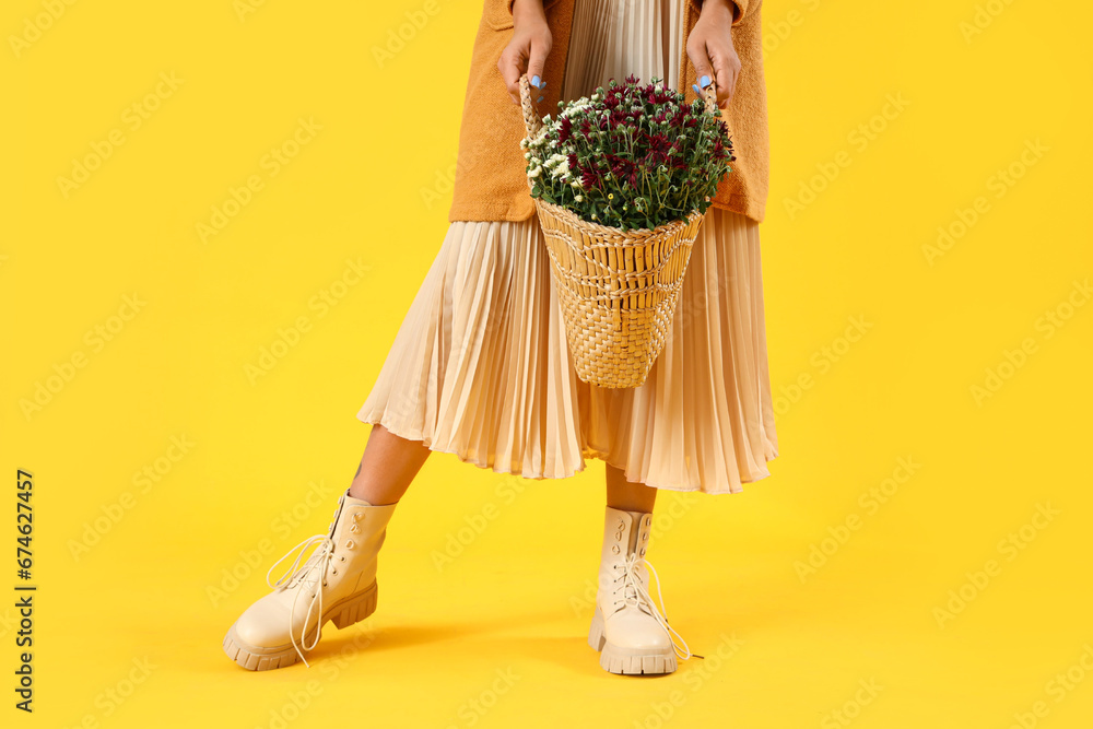 Young woman with chrysanthemum flowers on yellow background