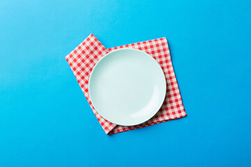 Sticker - Top view on colored background empty round blue plate on tablecloth for food. Empty dish on napkin with space for your design