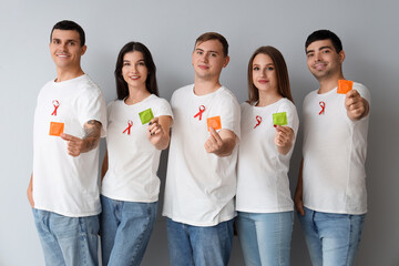 Wall Mural - Group of young people with red ribbons and condoms on grey background. World AIDS day concept