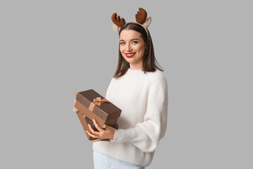 Wall Mural - Young woman holding Christmas gift boxes on grey background