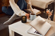 Cropped photo of young girl reading book and reaching for cup of coffee which is on coffee table with candle. Home comfort. concept of lifestyle, winter holiday season, autumn weekend, atmosphere,