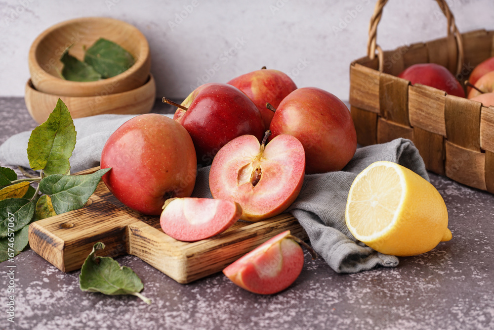 Wooden board with sweet pink apples and lemon on dark table