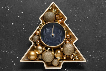 Wall Mural - Plate in shape of Christmas tree with alarm clock and balls on black background