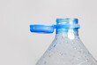 Close up of new cap attached to plastic bottle, connected to the neck of the bottle by solid tab attached to safety ring. They are intended to encourage recycling, as part of the fight against litter.