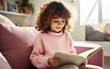© Malchevska Studio - Fair-skinned girl in a warm bright sweater reads a book while sitting on the sofa. Beautiful photo of a teenage female with a book.