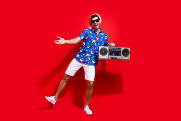 Poster - Full size photo of funky young man dance energetic boom box dressed santa claus print x-mas clothes isolated on red color background