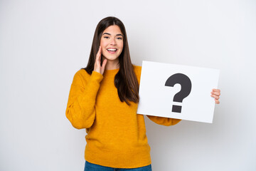 Wall Mural - Young Brazilian woman isolated on white background holding a placard with question mark symbol and shouting