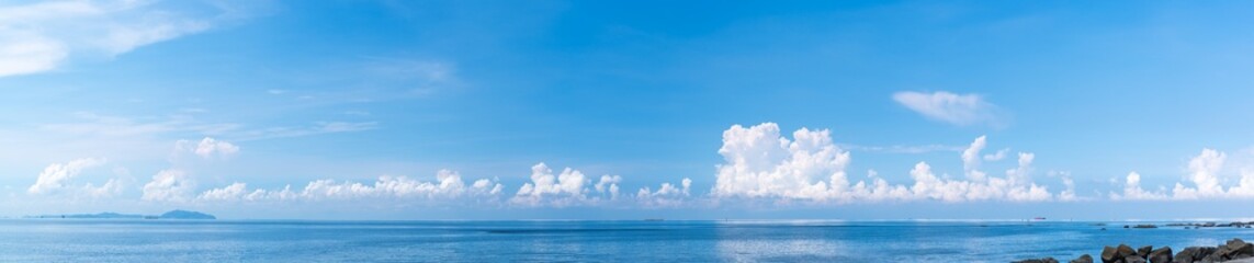 Wall Mural - panoramic blue sky with white fluffy clouds and sea