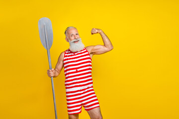 Sticker - Photo of imposing strong old man present his muscle biceps hand wear striped overalls hold surfing oar isolated on yellow color background