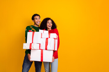 Wall Mural - Photo of funny cheerful people hold pile stack new year giftbox look empty space isolated on yellow color background