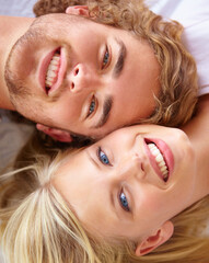 Poster - Portrait, love and smile with a couple on bed in their home together from above to relax while bonding. Face, happy or romantic with a young man and woman in the bedroom of their apartment closeup