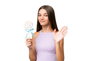 Poster - Teenager caucasian girl holding a lollipop over isolated background saluting with hand with happy expression