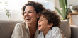 © AI_images - Happy young Latin mother and little son having fun on cozy couch in living room, overjoyed mum and preschool child tickling, cuddling, enjoying leisure time together