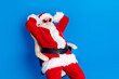 © deagreez - Photo portrait of mature pensioner man hands behind head sleepy dressed stylish santa claus costume coat isolated on blue color background