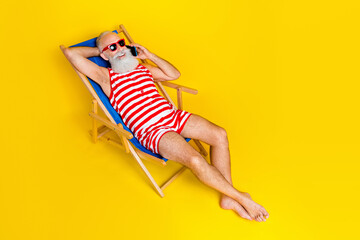 Wall Mural - Full length portrait of carefree aged man sunbathing lounger speak telephone isolated on yellow color background