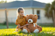 © bilanol - Pretty child girl tenderly embracing her teddy bear friend outdoors on green grass lawn. Concept of friendship values