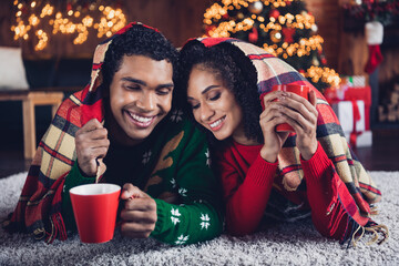 Canvas Print - Photo of two positive peaceful people closed eyes lay carpet floor covered blanket drink hot cacao festive decor lights house indoors