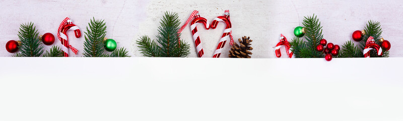 Poster - Evergreen fir tree twigs with red gift box and green twigs, flat lay layout wide border with copy space