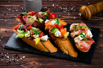 Wall Mural - Banquet menu bruschetta with beef slices, capers, cherry tomatoes, mozzarella, salmon, cucumber, lettuce.