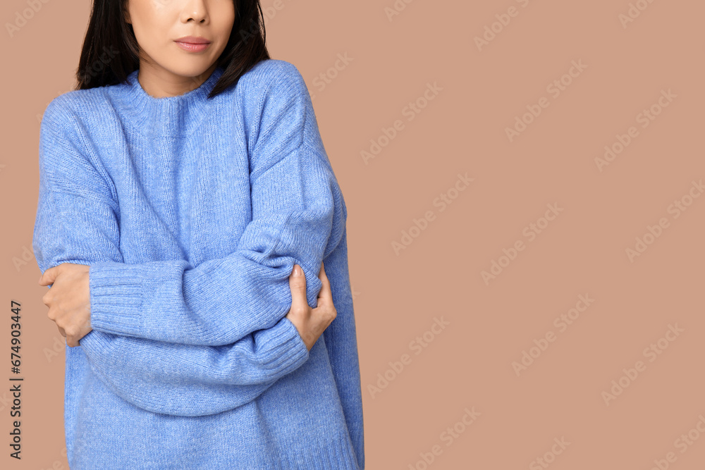 Young woman hugging herself on brown background, closeup