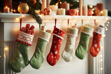Stockings Filled With Gifts Of Various Shapes And Sizes Hanging Near The Fireplace Decorated With Balls, Candles And Garland. Three Kings Day, Epiphany Day, Christmas.