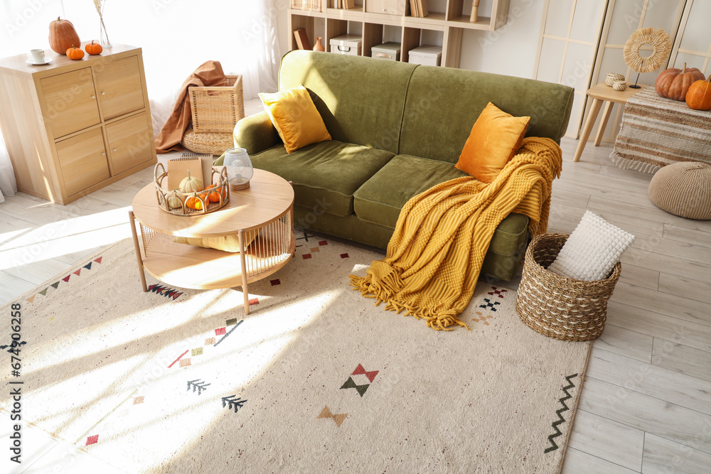 Interior of living room with green sofa and pumpkins