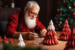© Maryna - Portrait of senior Santa Claus making origami Christmas tree at home