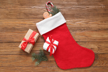 Sticker - Christmas sock with fir branches, gingerbread, candy cane and gift boxes on wooden background