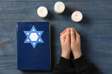 Wall Mural - Jewish woman with Torah and burning candles on dark wooden background