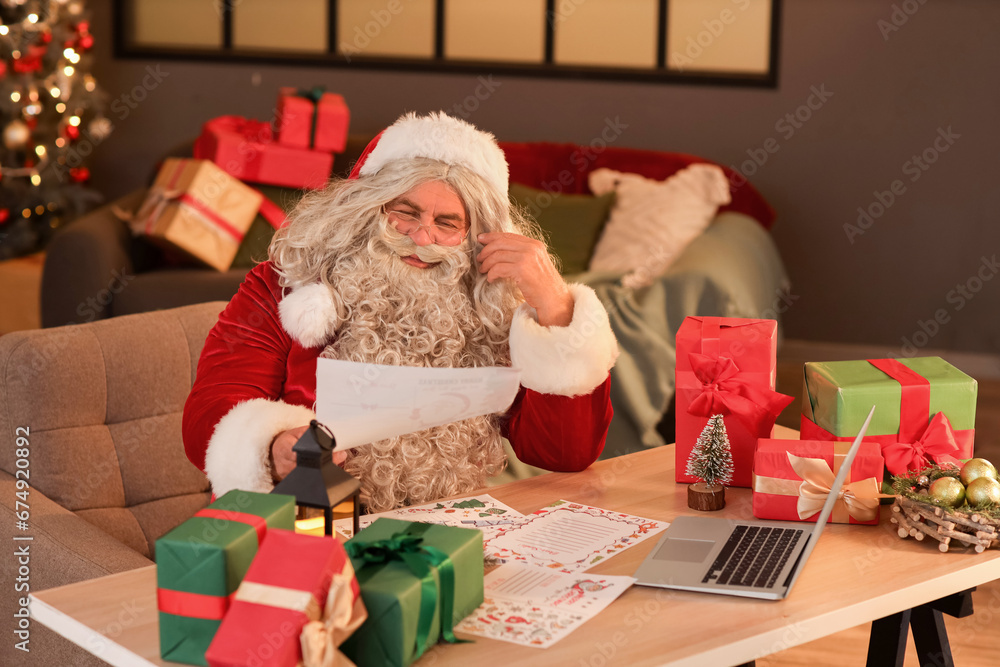 Santa Claus reading letter at home on Christmas eve