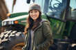Portrait of an Asian girl in a knitted hat and green jacket against the background of a large tractor. Agriculture concept.