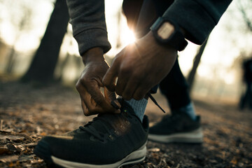 Wall Mural - Athlete Tying Running Shoes for Morning Training Outdoors