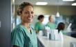 © piai - A female nurse wearing green scrubs smiling at a patient behind a counter in a bright medical laboratory