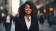 © pinkrabbit - portrait of a beautiful smiling white young black businesswoman boss in a black suit walking on a city street to his company office. blurry crowdy street background