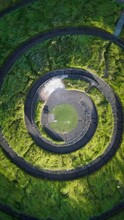 Vertical Drone View Above A Spiral-shaped Road Between The Green Vegetation