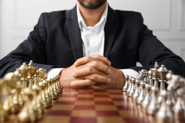 Poster - Man with chess pieces on checkerboard before game indoors, closeup