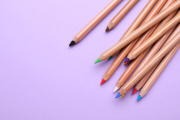 Poster - Many colorful pastel pencils on violet background, flat lay and space for text. Drawing supplies