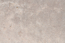 Detail Of A Section Of Weathered Concrete Sidewalk With A Rough Texture, Gray Colors, And Thin Cracks And Chips In The Surface.