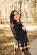 © Mila - A beautiful girl in jeans and a plaid shirt walks in a birch grove. Portraits of a brunette girl in nature, in the autumn forest