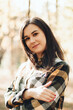 © Mila - A beautiful girl in jeans and a plaid shirt walks in a birch grove. Portraits of a brunette girl in nature, in the autumn forest