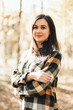 © Mila - A beautiful girl in jeans and a plaid shirt walks in a birch grove. Portraits of a brunette girl in nature, in the autumn forest