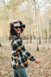 © Mila - A beautiful girl in jeans and a plaid shirt walks in a birch grove. Portraits of a brunette girl in nature, in the autumn forest